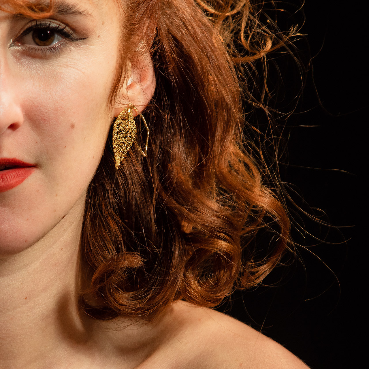 Moitié de visage d'une jeune femme rousse portant le modèle de boucle d'oreille Folÿs 4, bijou brodé à la main signé Marie Archambaud.