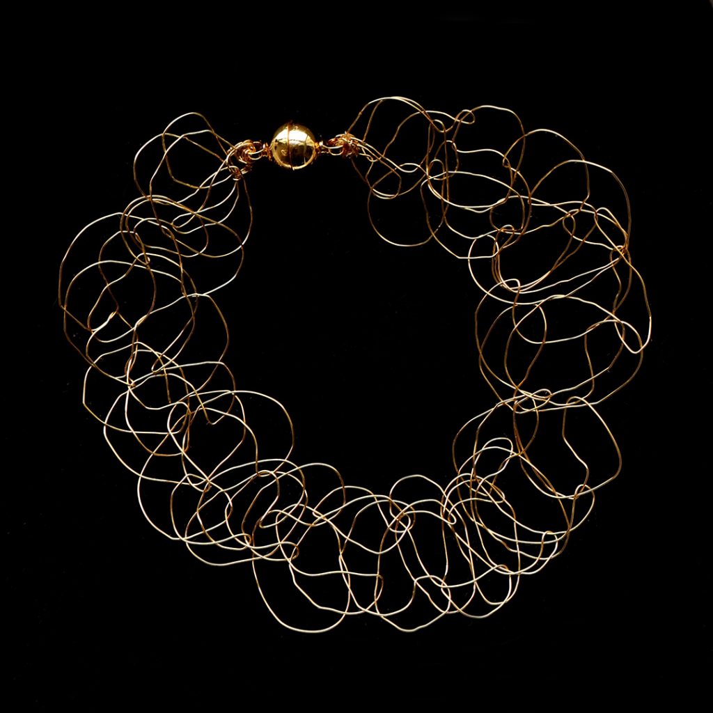 Bracelet Lumio sur fond noir, en fil de cuivre plaqué or jaune, fin et élégant.