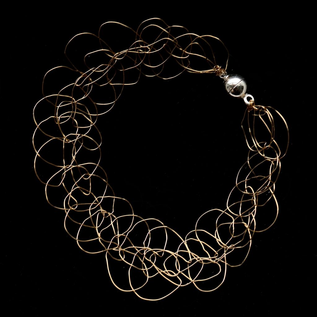Bracelet Lumio sur fond noir, en fil de cuivre plaqué or champagne, fin et élégant.