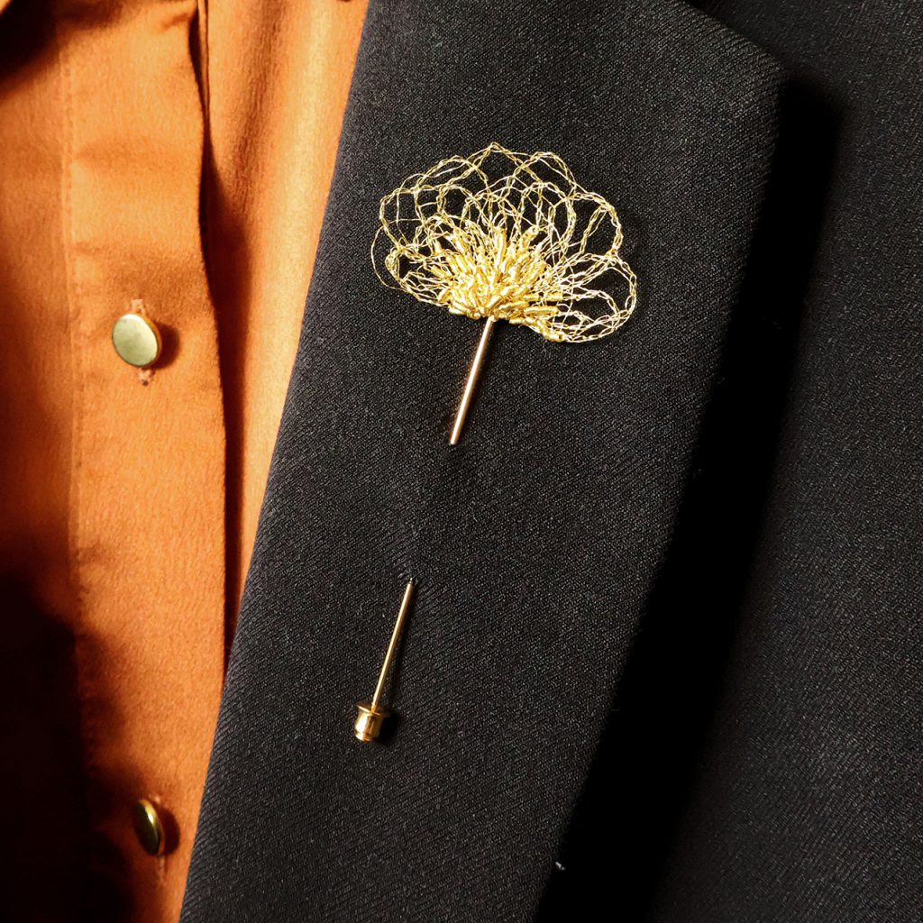 Broche boutonnière Aurora disposée sur veste de costume noir