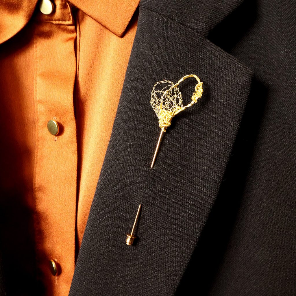 Broche boutonnière Coccum disposée sur veste de costume noir
