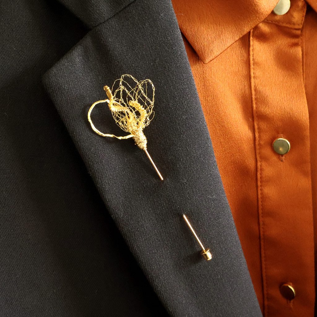 Broche boutonnière Iridis disposée sur veste de costume noir