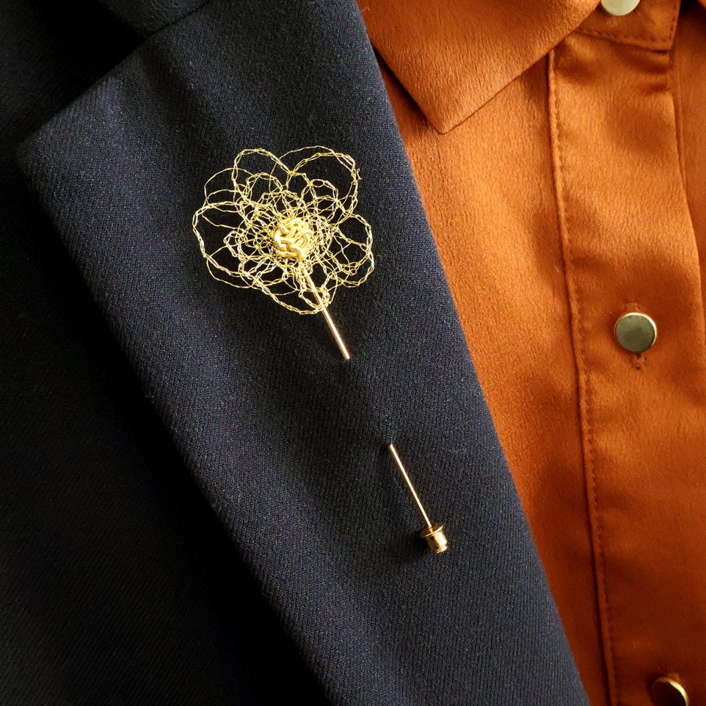 Broche boutonnière Pavon disposée sur veste de costume noir