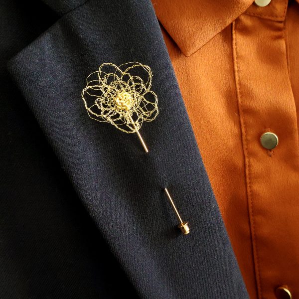 Broche boutonnière Pavon disposée sur veste de costume noir