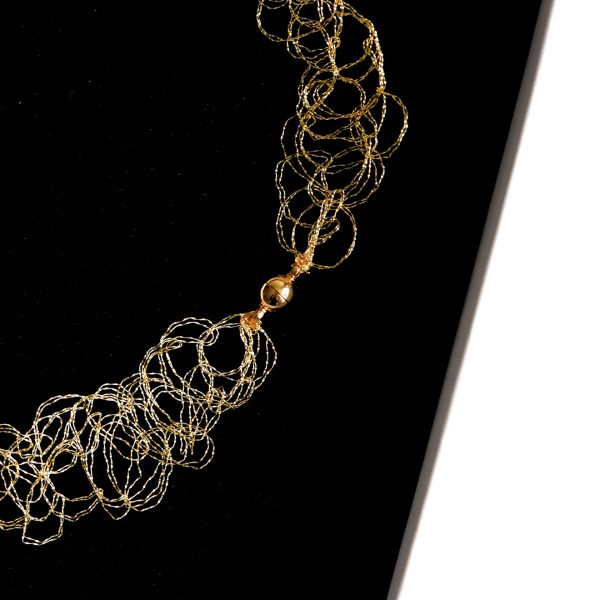 Collier Lumi dans sa boite à bijou blanche et mousse noire faisant ressortir le doré de la maille métallique.