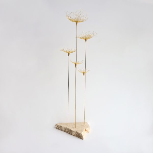 Sculpture Pavon sur fond gris. Cinq tiges métalliques surmontées de fleurs brodées au fil d'or et piquées sur pierre de tufeau.