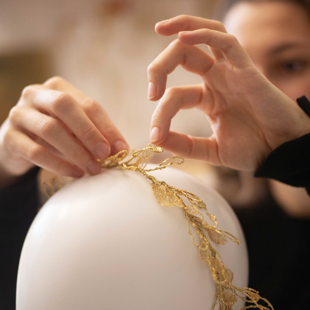 Mains repositionnant des feuilles brodées au fil d'or d'une couronne de cheveux