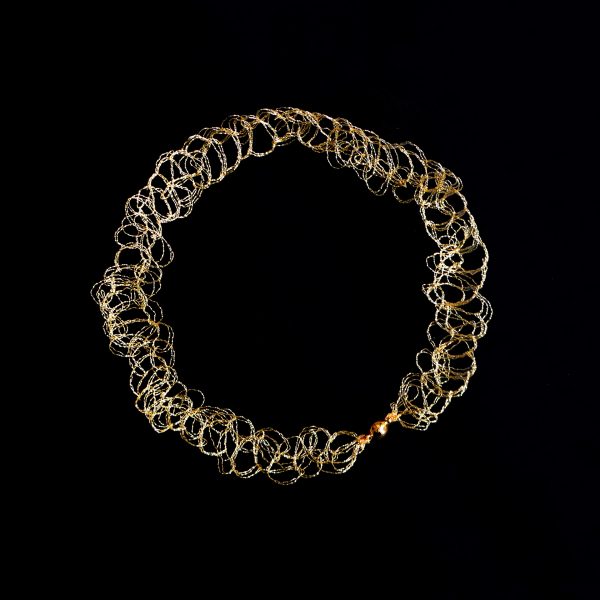 Collier ras de cou Lumi or sur fond noir. Il est réalisé à la main par une technique de maille métallique propre à l'atelier Marie Archambaud.